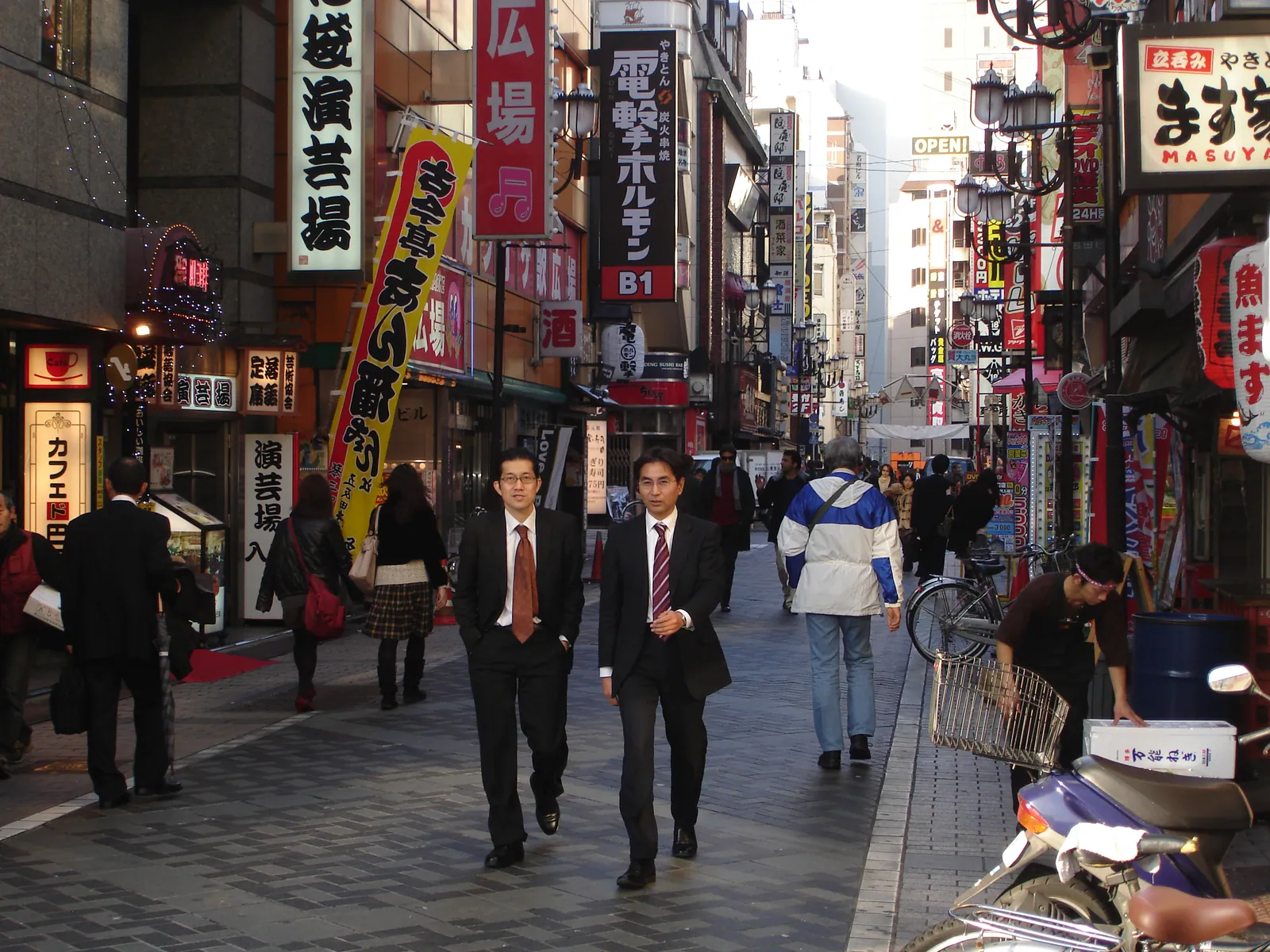 Pedestrians walking past shops and signs on a Tokyo street